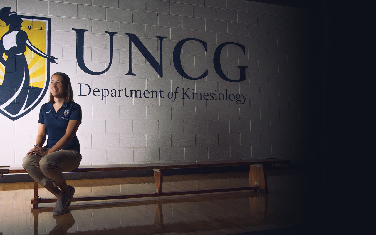 UNCG Researcher infront of logo